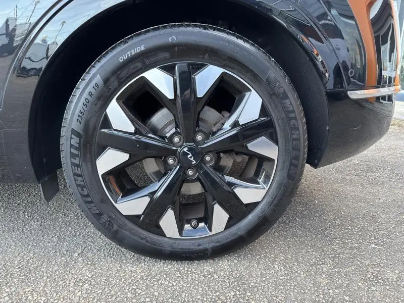 Gros plan sur la roue avant droite du KIA SPORTAGE noir Basalte métallisé avec jante alliage 19 pouces bicolore.