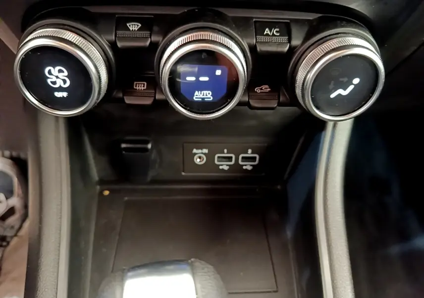 Gros plan sur la console centrale du Renault Captur gris foncé 2022, avec commandes climatisation et ports USB visibles.