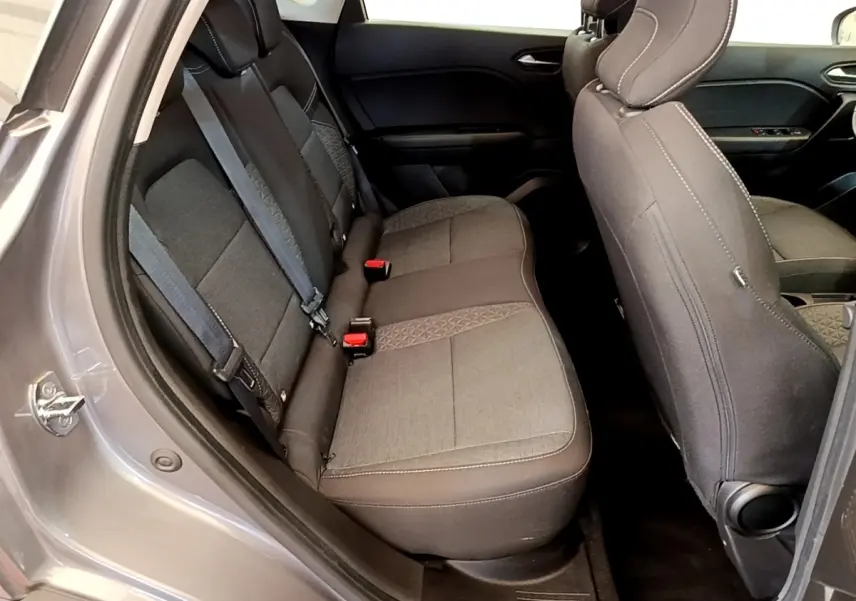 Vue intérieure côté arrière gauche du Renault Captur gris foncé, montrant la banquette arrière en tissu avec ceintures de sécurité.