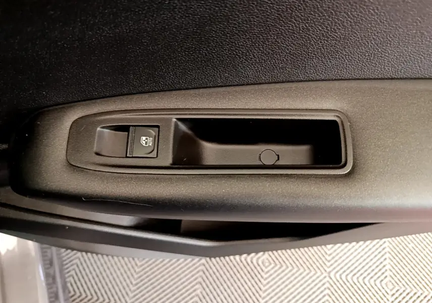Gros plan sur la commande de lève-vitre côté conducteur du Renault Captur Zen E-Tech hybride gris foncé 2022.
