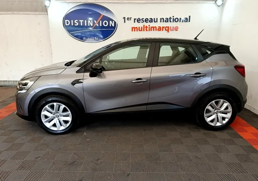 Profil droit d’un Renault Captur Zen E-Tech hybride gris foncé 2022, avec toit noir et jantes argentées, en intérieur showroom.