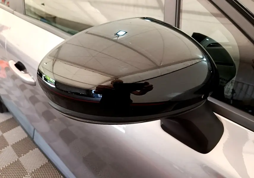 Gros plan sur le rétroviseur droit noir brillant du Renault Captur gris foncé, vue latérale côté passager.