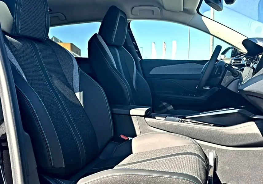 Vue intérieure côté gauche du Peugeot 408 Hybrid 145 allure e-dcs6 2025, sièges tissu noir et console centrale.