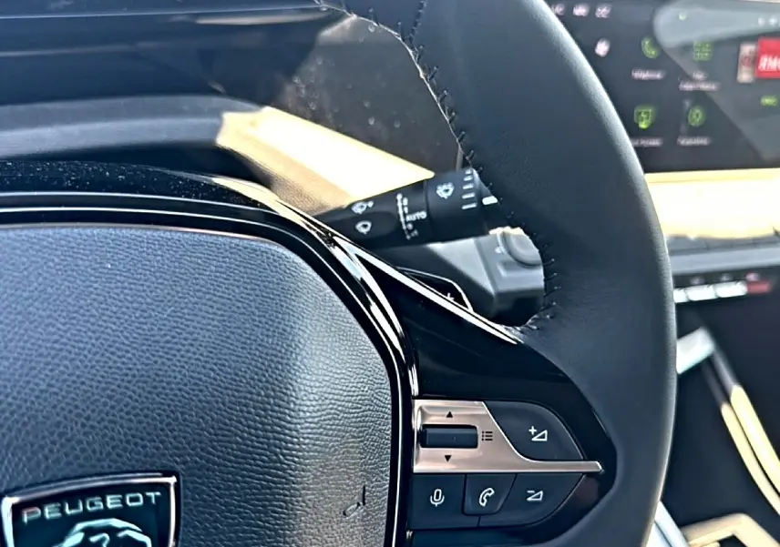 Gros plan sur le volant cuir noir du Peugeot 408 Hybrid 145 allure, avec commandes audio et téléphone intégrées.
