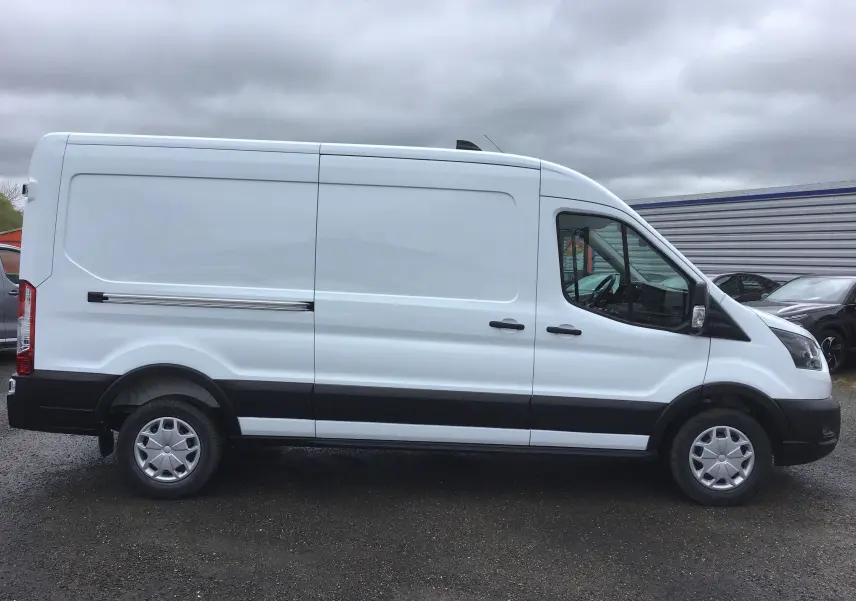 Profil côté droit d'un fourgon Ford Transit blanc 2023 avec bande noire basse et jantes acier.