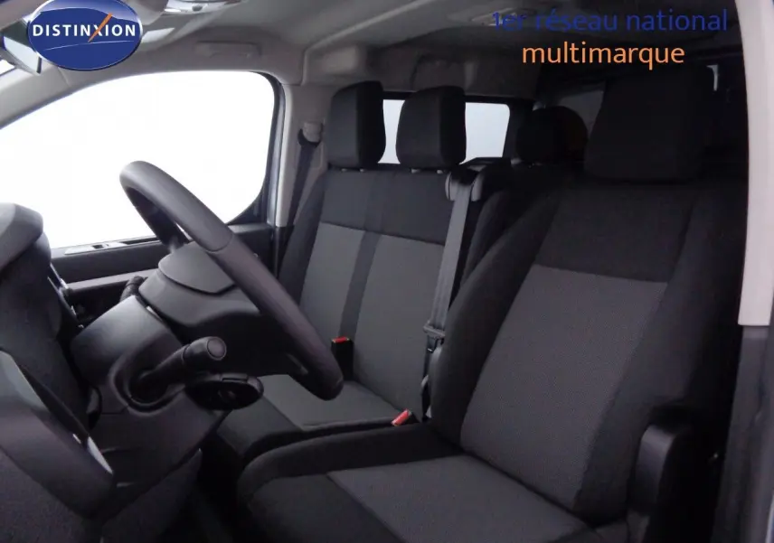 Vue intérieure côté conducteur du Peugeot Expert gris avec sièges tissu gris et noir, volant et ceintures visibles.