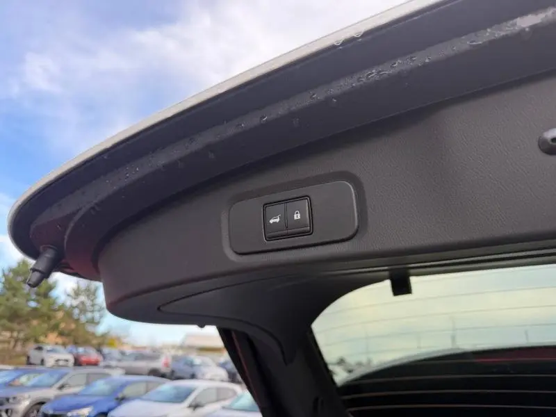 Gros plan sur le bouton d'ouverture et de verrouillage du hayon du Nissan Qashqai blanc Hybrid e-POWER 2025.