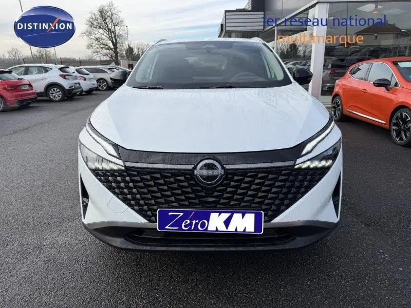 Vue frontale d'un Nissan Qashqai Hybrid e-POWER blanc 2025 avec calandre noire texturée et phares LED allumés.