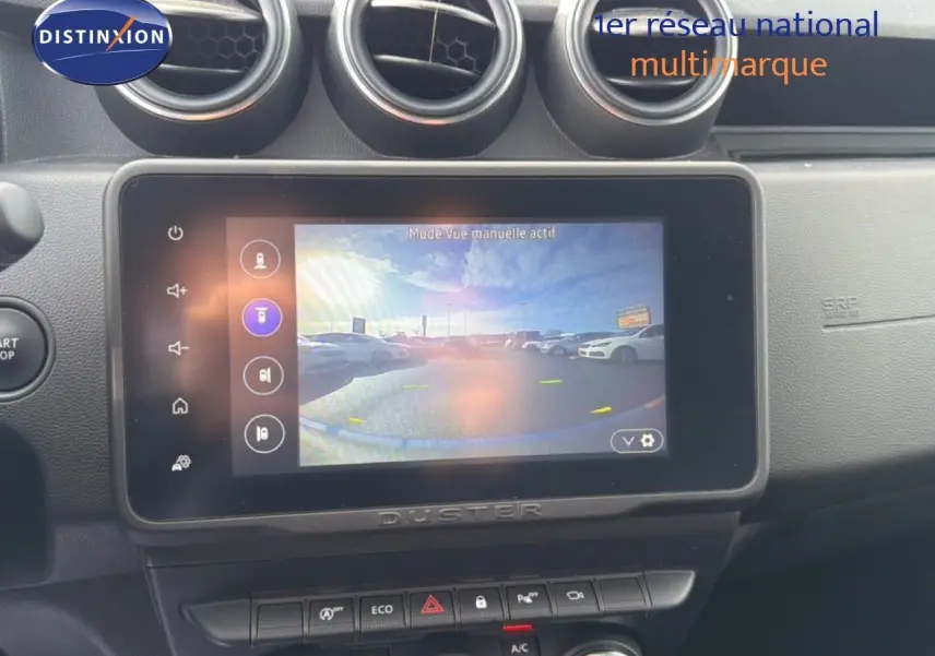 Vue intérieure centrée sur l'écran tactile du tableau de bord du Dacia Duster 2022, avec commandes et aérateurs visibles.