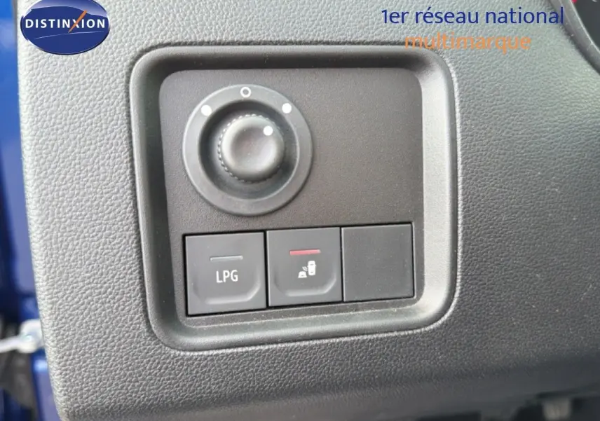 Gros plan sur les commandes intérieures noires du tableau de bord du Dacia Duster bleu iron, avec bouton LPG visible.