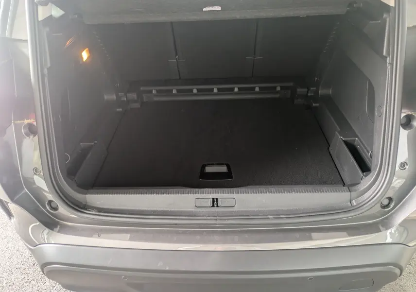 Coffre ouvert vu de l'arrière d'un Citroën C5 Aircross hybride gris platinium, espace de chargement vide et éclairage intérieur allumé.