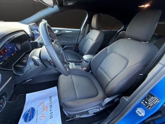 Vue intérieure côté conducteur de la Ford Focus 1.5 EcoBoost 150ch ST-Line 2022, sièges noirs avec surpiqûres rouges.