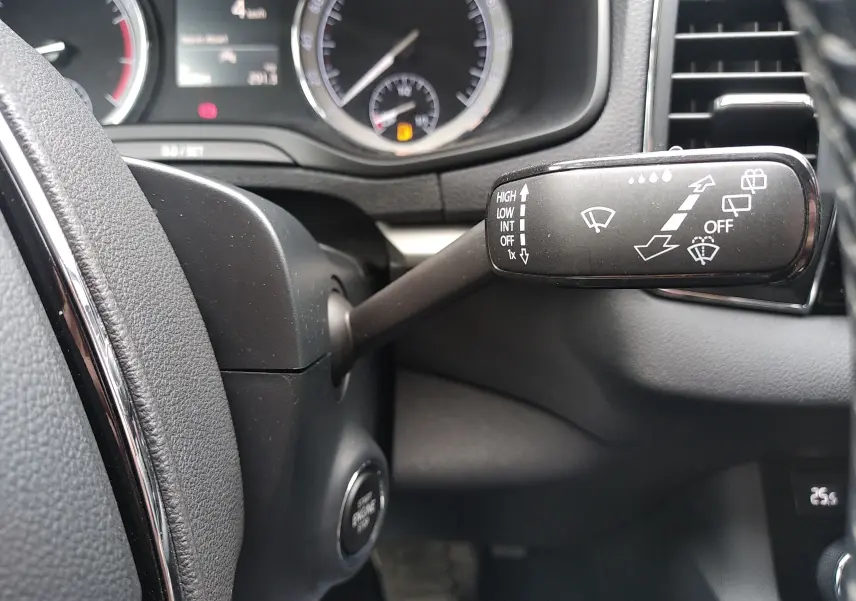 Gros plan sur la manette d'essuie-glace à droite du volant dans l'habitacle gris foncé d'un Skoda Karoq 2021.