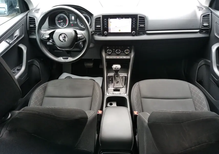 Vue intérieure avant du Skoda Karoq gris 2021, avec tableau de bord moderne, écran tactile et volant multifonction.
