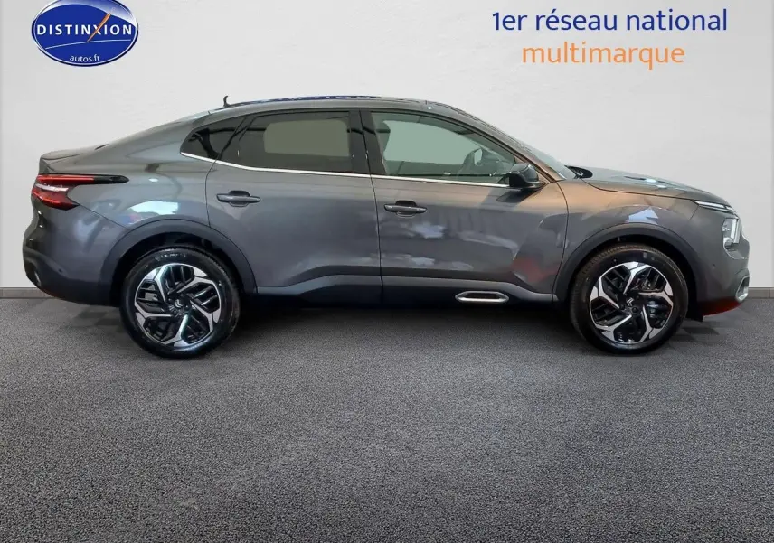 Profil droit d'une Citroën C4 X 2023 gris platinium métal avec jantes bi-ton et lignes fluides élégantes.