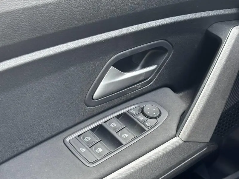 Gros plan sur la porte avant gauche intérieure du Dacia Bigster blanc, montrant les commandes des vitres et la poignée argentée.