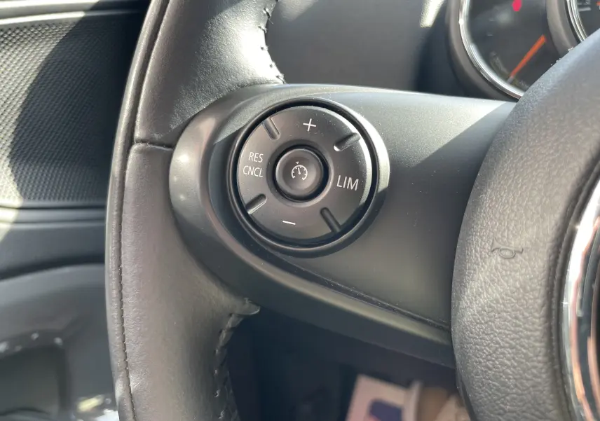Gros plan sur les commandes de régulateur de vitesse au volant cuir noir d'une MINI Countryman F60 Moonwalk Grey 2019.