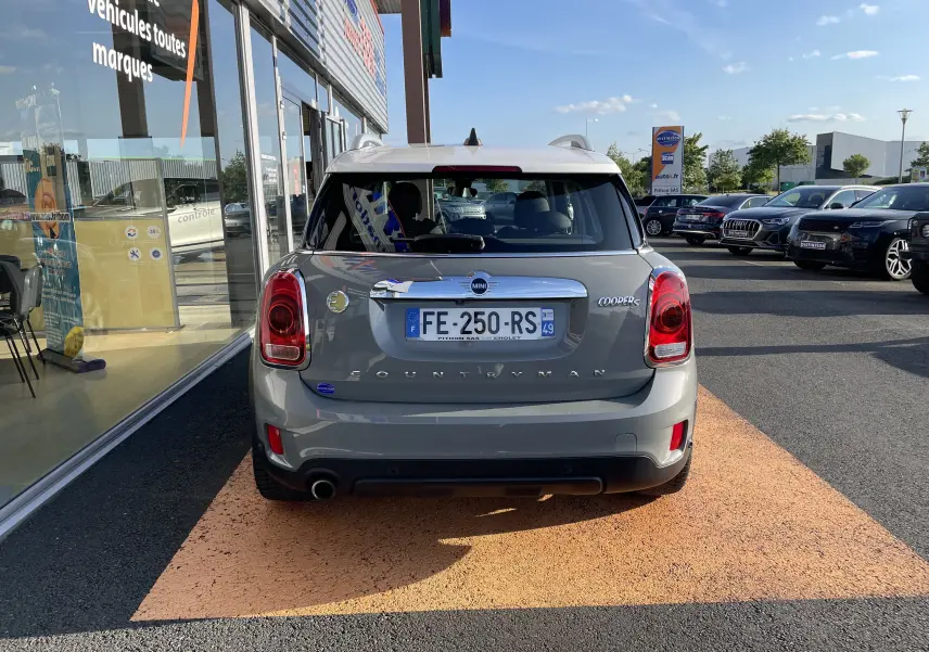 Vue arrière d'une MINI Countryman F60 Cooper SE hybride rechargeable en Moonwalk Grey stationnée devant un showroom.