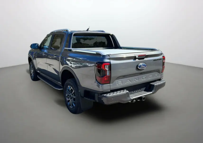 Ford Ranger 2025 gris carbone en vue 3/4 arrière droit, avec benne couverte et logo Wildtrak visible.