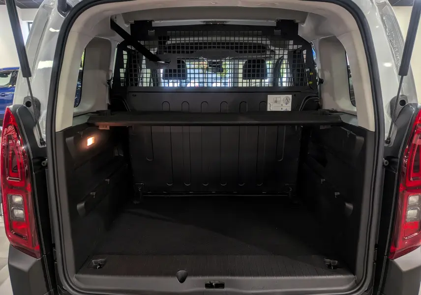 Vue arrière ouverte du Citroën Berlingo Blanc Glacier 2025, montrant le coffre spacieux avec séparation grillagée et éclairage intérieur.