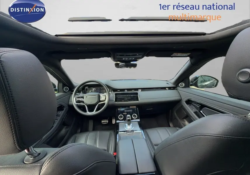 Vue intérieure avant du Range Rover Evoque 2023 noir, montrant le tableau de bord, le volant et la console centrale en cuir.