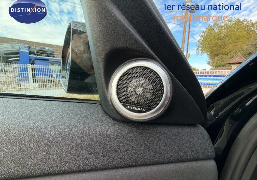 Gros plan sur l'enceinte Meridian intégrée à la porte côté gauche d'un Range Rover Evoque Santorini Black 2023.