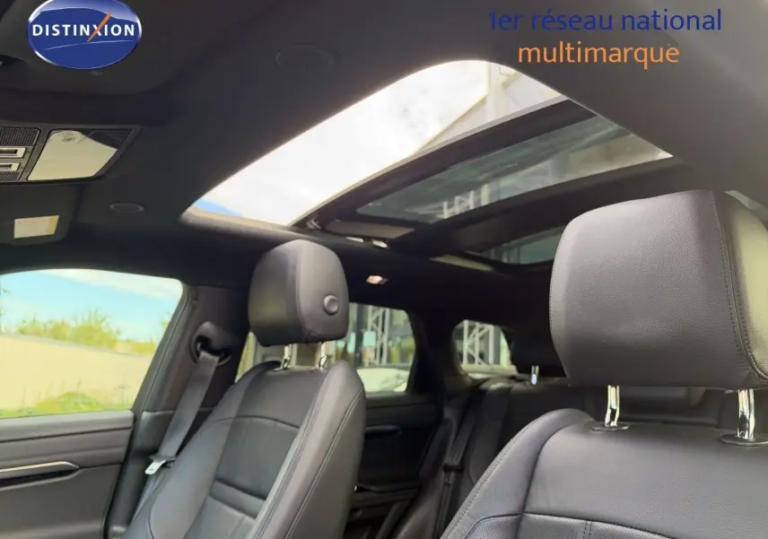 Intérieur du Range Rover Evoque 2023 en cuir noir, vue des sièges avant avec toit ouvrant panoramique ouvert.