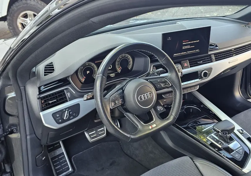 Intérieur de l'Audi A5 Sportback 2022 vu côté conducteur, volant sport en cuir perforé et tableau de bord moderne.