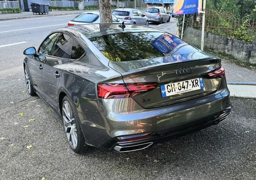 Vue 3/4 arrière droite d'une Audi A5 Sportback 2022 gris Daytona avec jantes alliage et feux LED distinctifs.