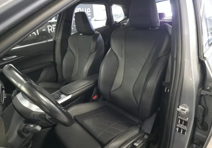 Vue intérieure côté conducteur de la BMW Série 2 218i M Sport 2023 avec sièges sport Similicuir noir et accoudoir central.