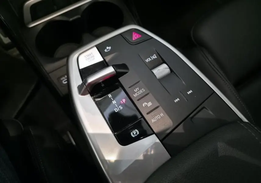 Gros plan sur la console centrale noire et argentée du BMW Série 2 218i Active Tourer avec commandes de boîte auto et volume.