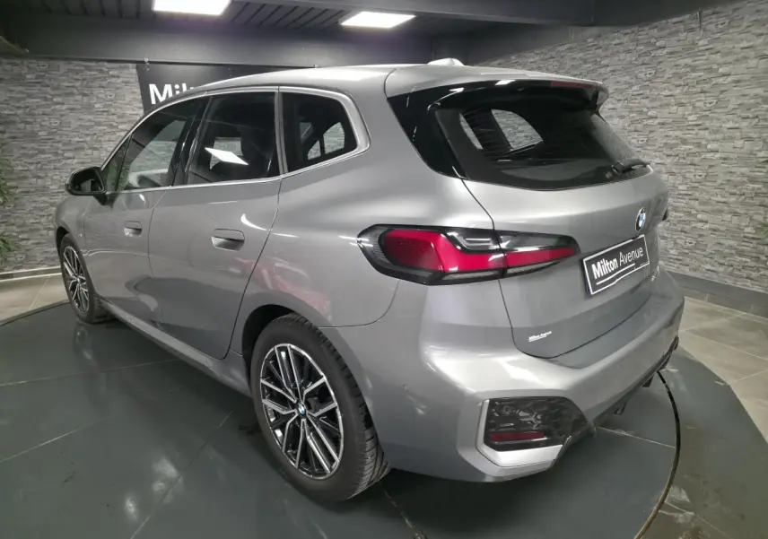 BMW Série 2 218i Active Tourer gris métallisé vue 3/4 arrière droit avec jantes bicolores et feux LED arrière