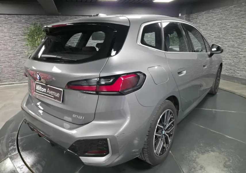 Vue 3/4 arrière droite d'une BMW Série 2 218i Active Tourer gris métallisé avec jantes alliage 18 pouces.