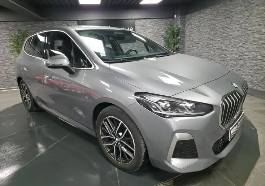 BMW Série 2 218i Active Tourer gris métallisé vue 3/4 avant avec calandre chromée et jantes M bicolores.