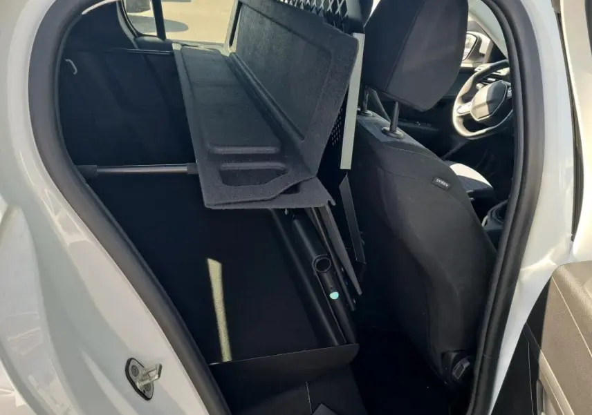 Vue intérieure côté gauche de la Peugeot 208 Affaire blanche, montrant la banquette rabattue et la grille de séparation.