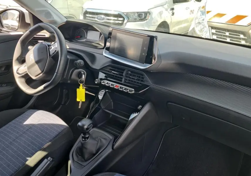 Vue intérieure côté conducteur du Peugeot 208 Affaire blanc, montrant le volant, la console centrale avec écran tactile et boîte manuelle.