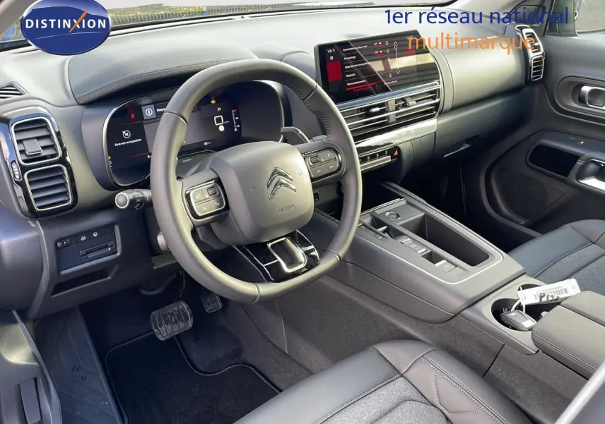 Intérieur de la Citroën C5 Aircross 2025, vue côté conducteur, tableau de bord moderne avec écran tactile et volant multifonction.