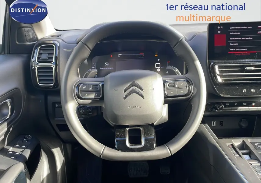 Vue intérieure centrée sur le volant cuir du Citroën C5 Aircross 2025 avec tableau de bord digital et écran tactile.