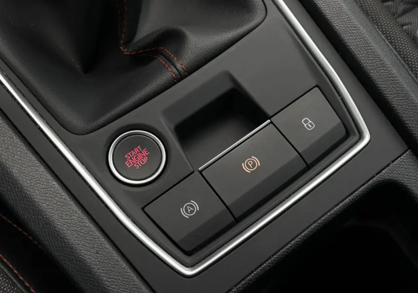 Gros plan sur la console centrale noire du SEAT Leon 2025, avec bouton Start Engine Stop et commandes électroniques.