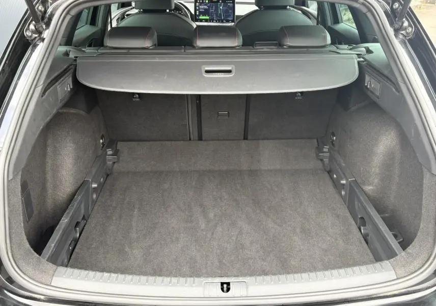 Coffre ouvert vu de l'arrière d'une SEAT Leon 2025 Noir Minuit, avec cache-bagages et sièges arrière visibles.