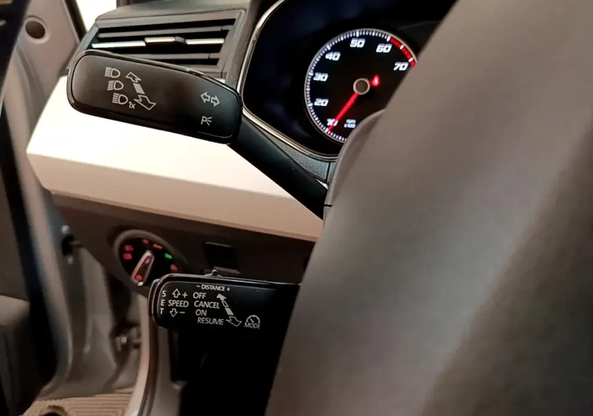 Gros plan sur le volant cuir et alu gris clair d’un SEAT Arona 2019, avec commandes au volant et tableau de bord éclairé.