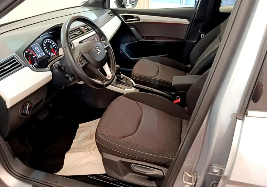 Intérieur avant droit d’un SEAT Arona gris clair 2019, volant cuir multifonctions et tableau de bord digital visible.
