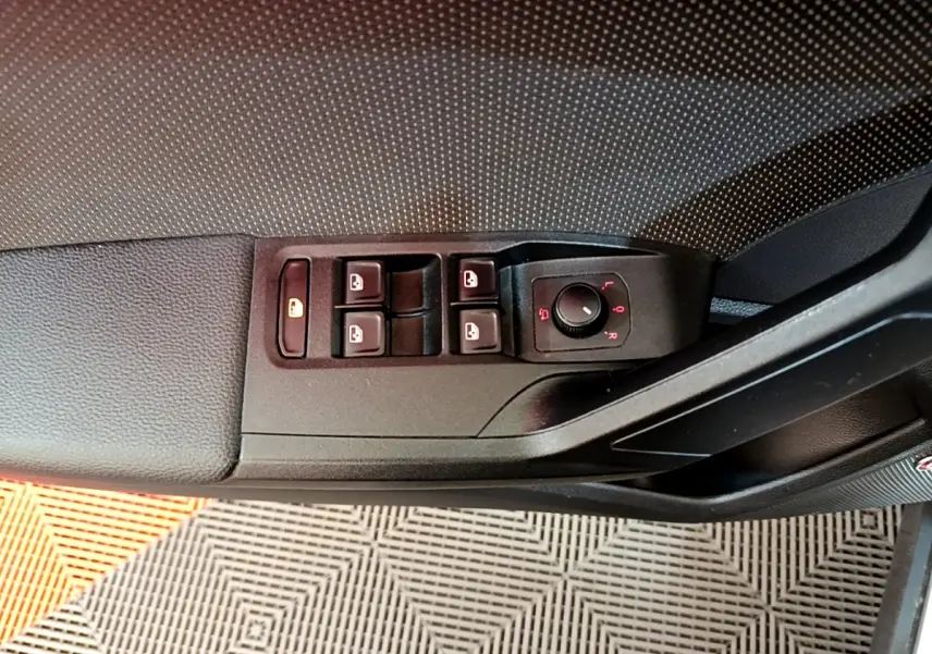 Gros plan sur la commande des vitres et rétroviseurs côté conducteur d'une SEAT Arona gris clair, intérieur noir.