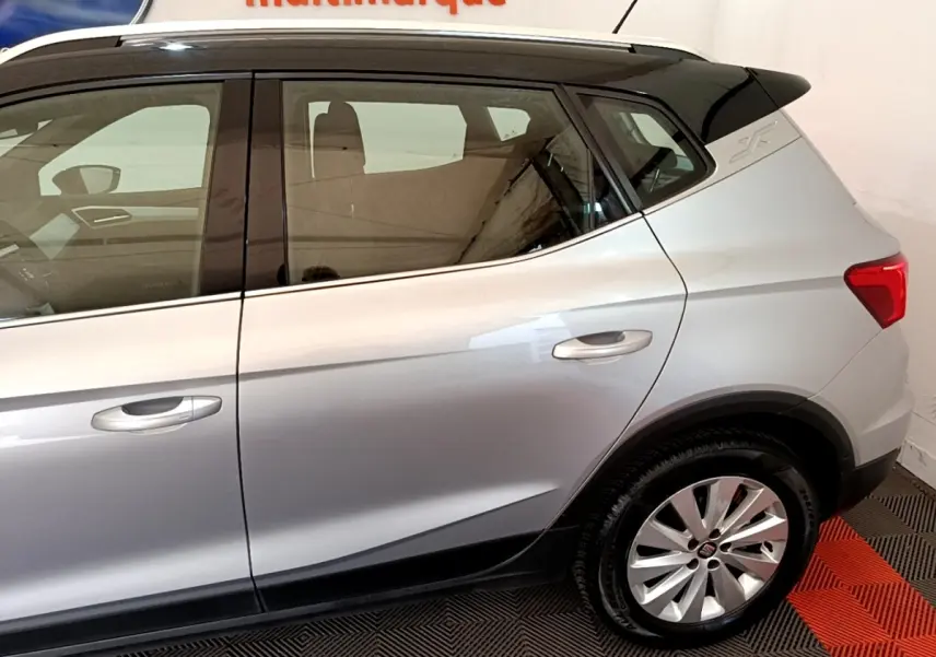 Vue latérale droite d'un SEAT Arona gris clair avec jantes alliage et toit noir contrasté.
