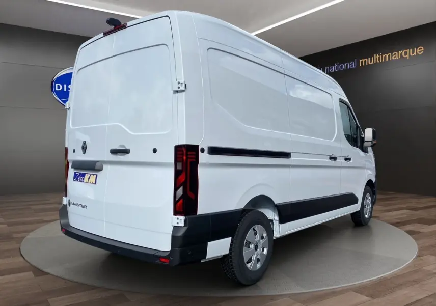 Renault Master blanc en vue 3/4 arrière droit, fourgon utilitaire avec feux arrière verticaux et protections noires.