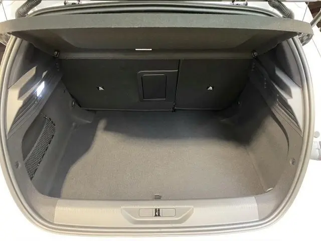 Vue intérieure du coffre spacieux et propre de la Peugeot 308 blanche, avec banquette arrière rabattable visible en arrière-plan.