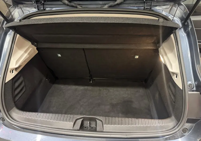 Coffre ouvert vu de l'arrière d'une Renault Clio V Business gris titanium, montrant l'espace de chargement vide et propre.
