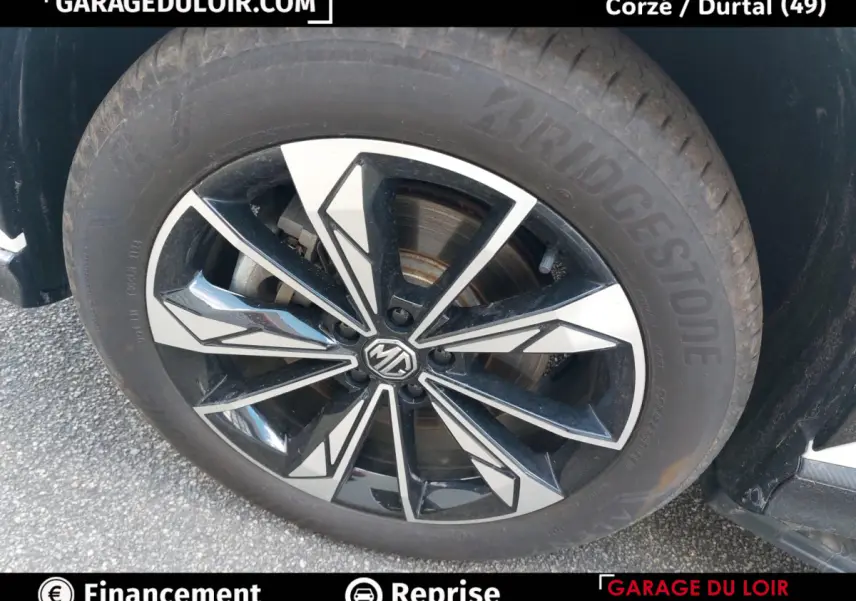 Gros plan sur la roue avant droite avec jante noire et argentée au design géométrique du MG Motor EHS hybride rechargeable.