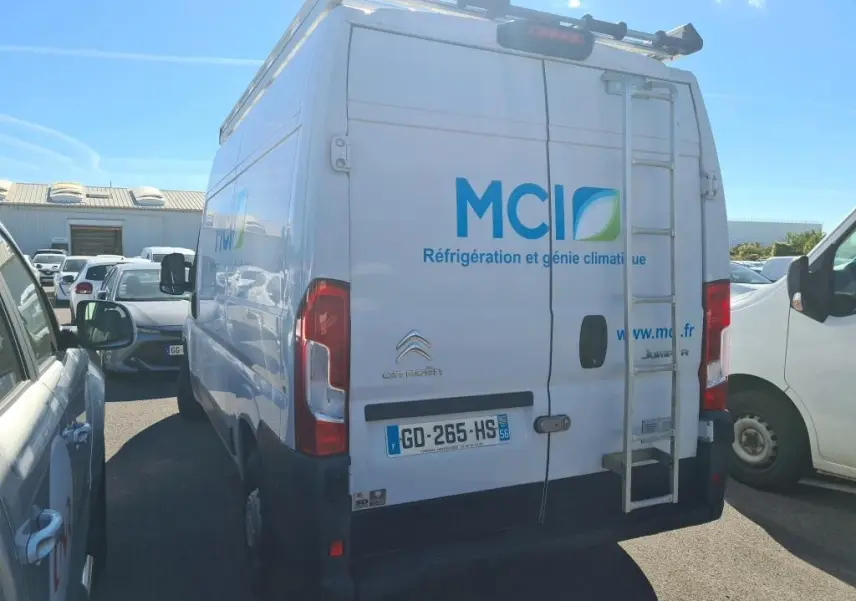 Vue arrière d’un Citroën Jumper blanc avec échelle et marquage MCI sur porte arrière, stationné en extérieur.