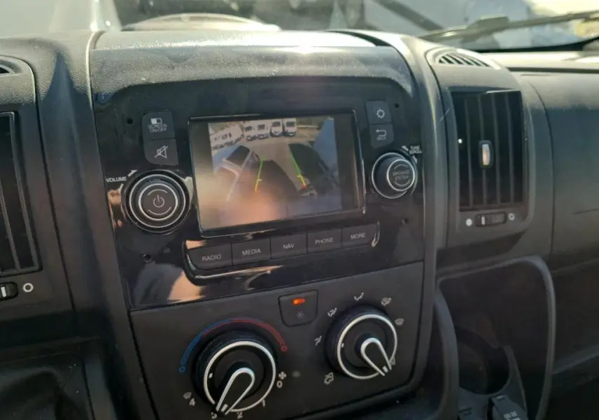Vue rapprochée de la console centrale du Citroën Jumper blanc, écran de caméra de recul et commandes climatisation visibles.